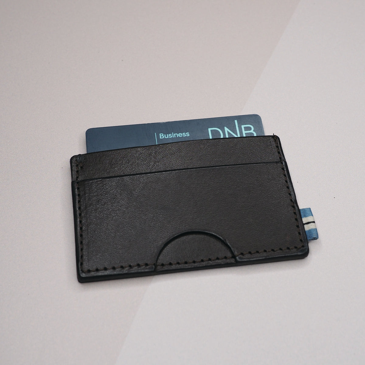 Kortholder i brunt skinn og blå tag
